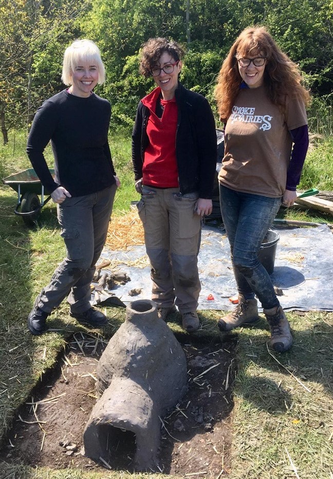 Chloe Duckworth, Eleonora Montanari, and Victoria Lucas stand behind one of the reconstructed bead furnaces